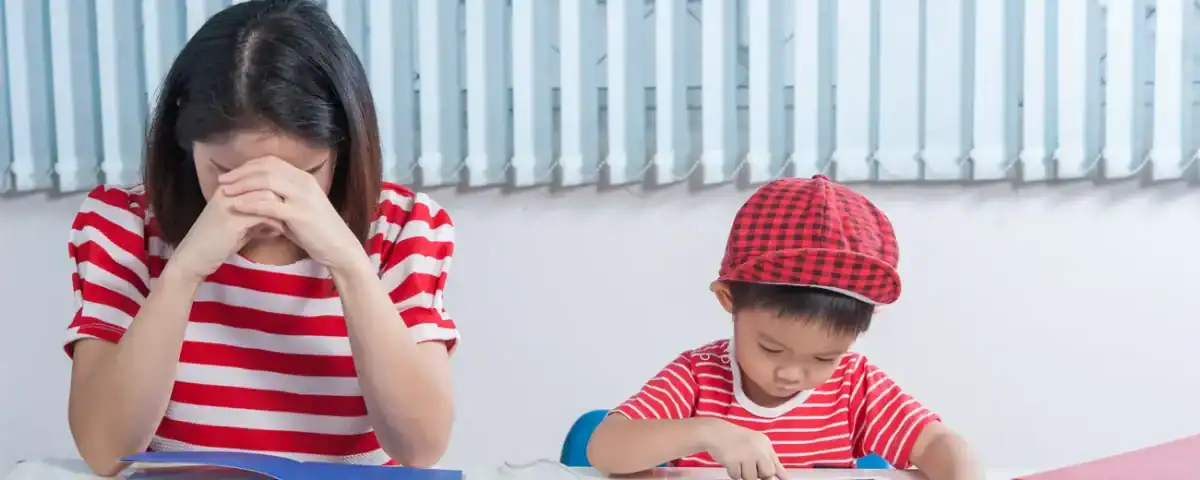 Asian boy playing on a tablet; his mother is frustrated