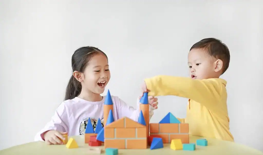 Asian girl and baby boy playing with wooden toys