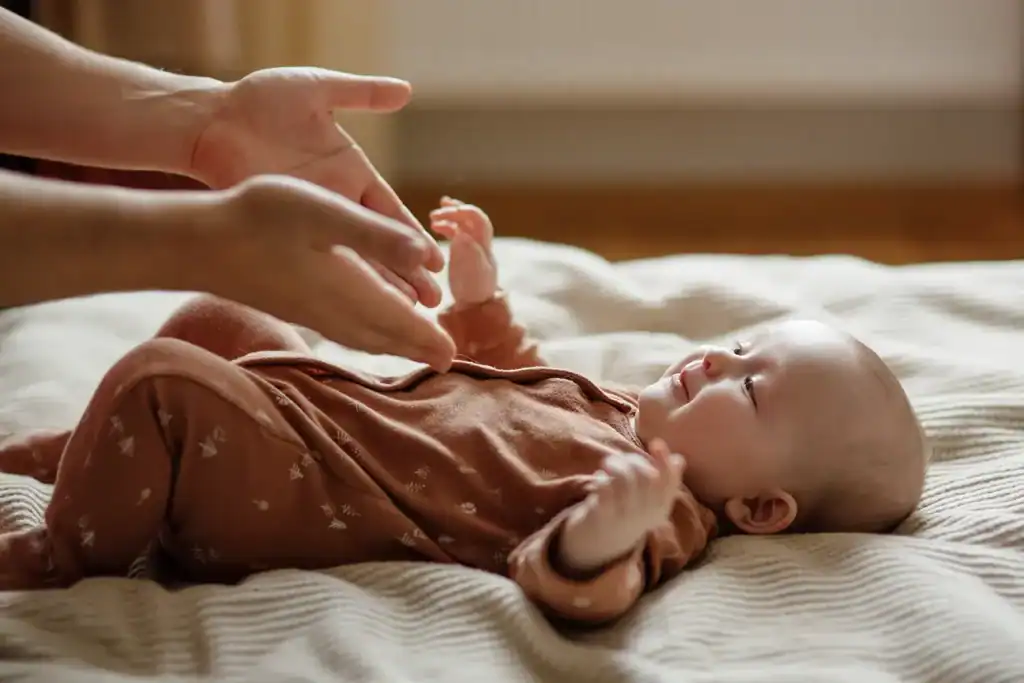 Close-up of parents' hands with a newborn baby lying in bed—a family scene illustrating baby care